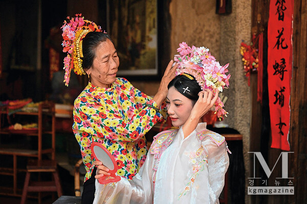 A tourist (right) is wearing flowery headwear at Xunpu Village of Quanzhou City, southeast China